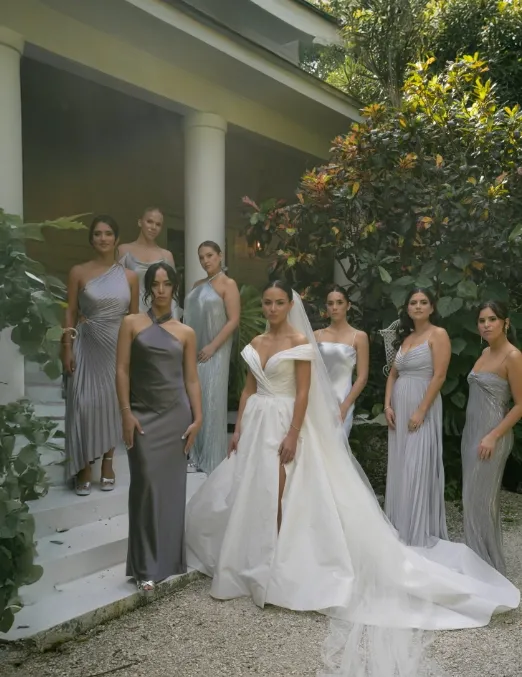 Bride and eight bridesmaids in grey gowns posed outside a columned porch