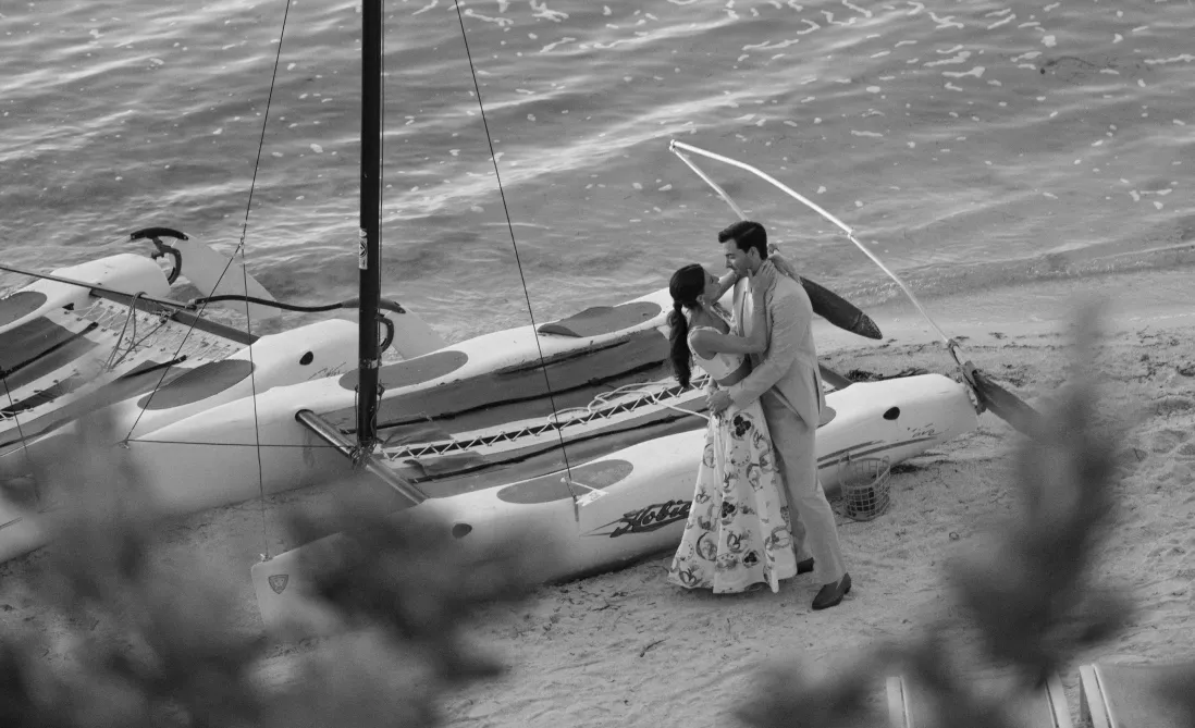 Couple embracing on a beach beside catamarans pulled up on the sand