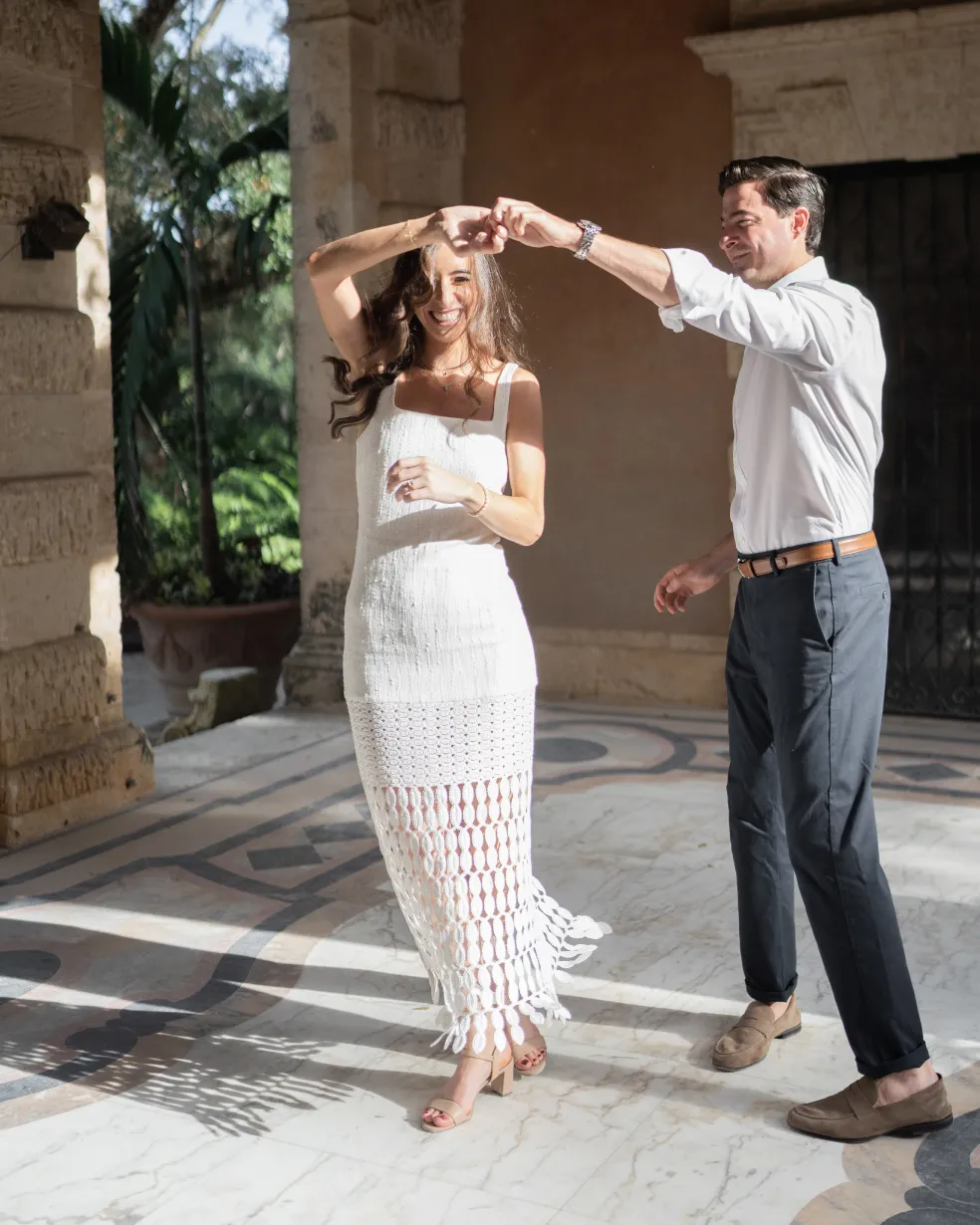 Man twirling a laughing woman on a marble loggia with mosaic floor