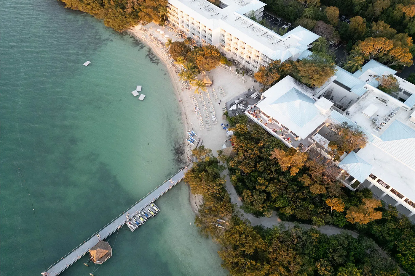 Aerial view of a beachfront resort with a long pier and turquoise shallows