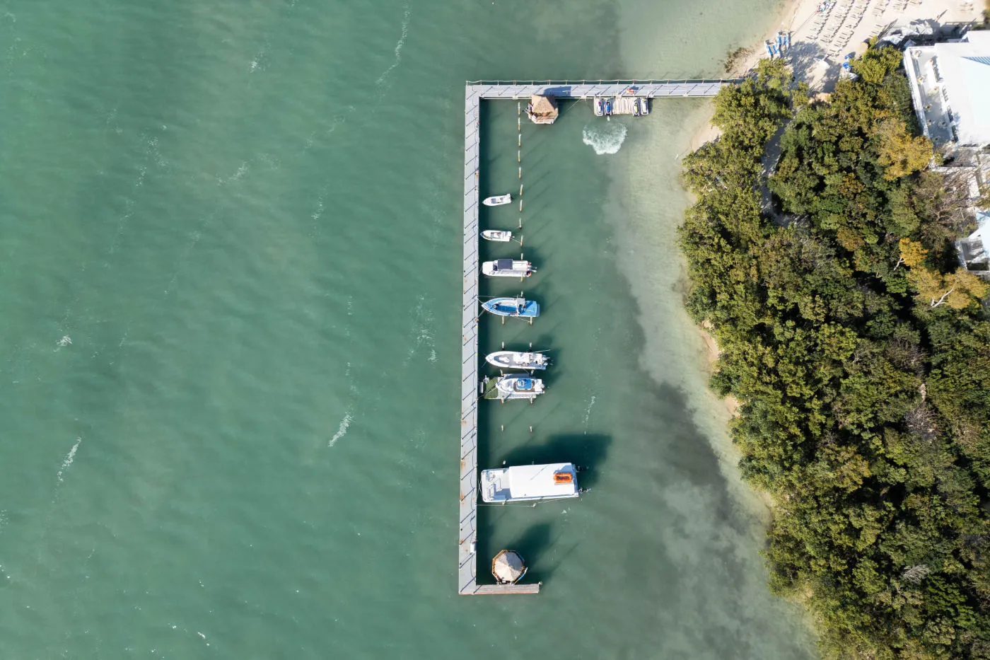 Aerial view of small boats moored along a dock on turquoise water
