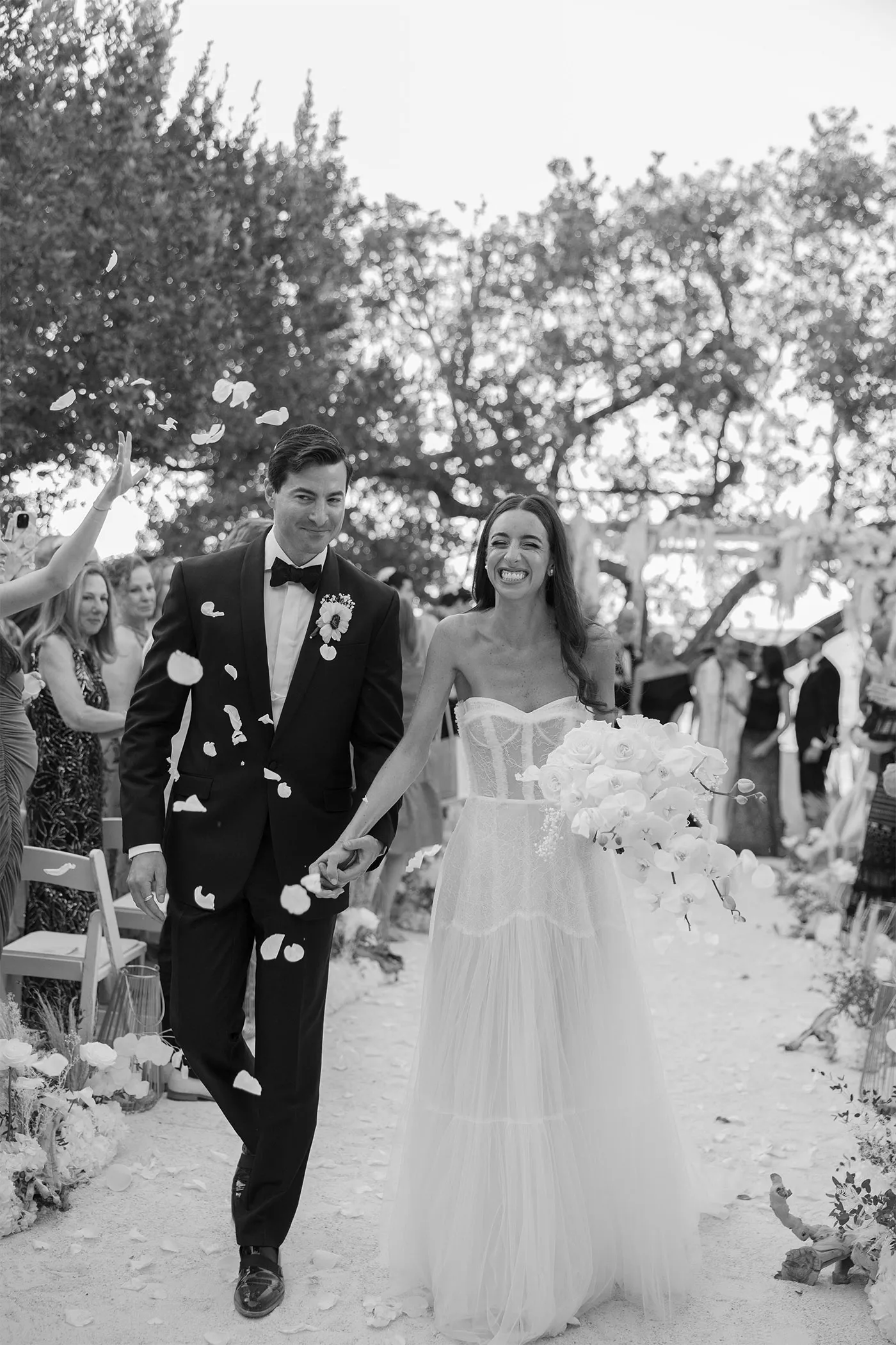 Bride and groom walking back up the aisle through falling petals as guests cheer