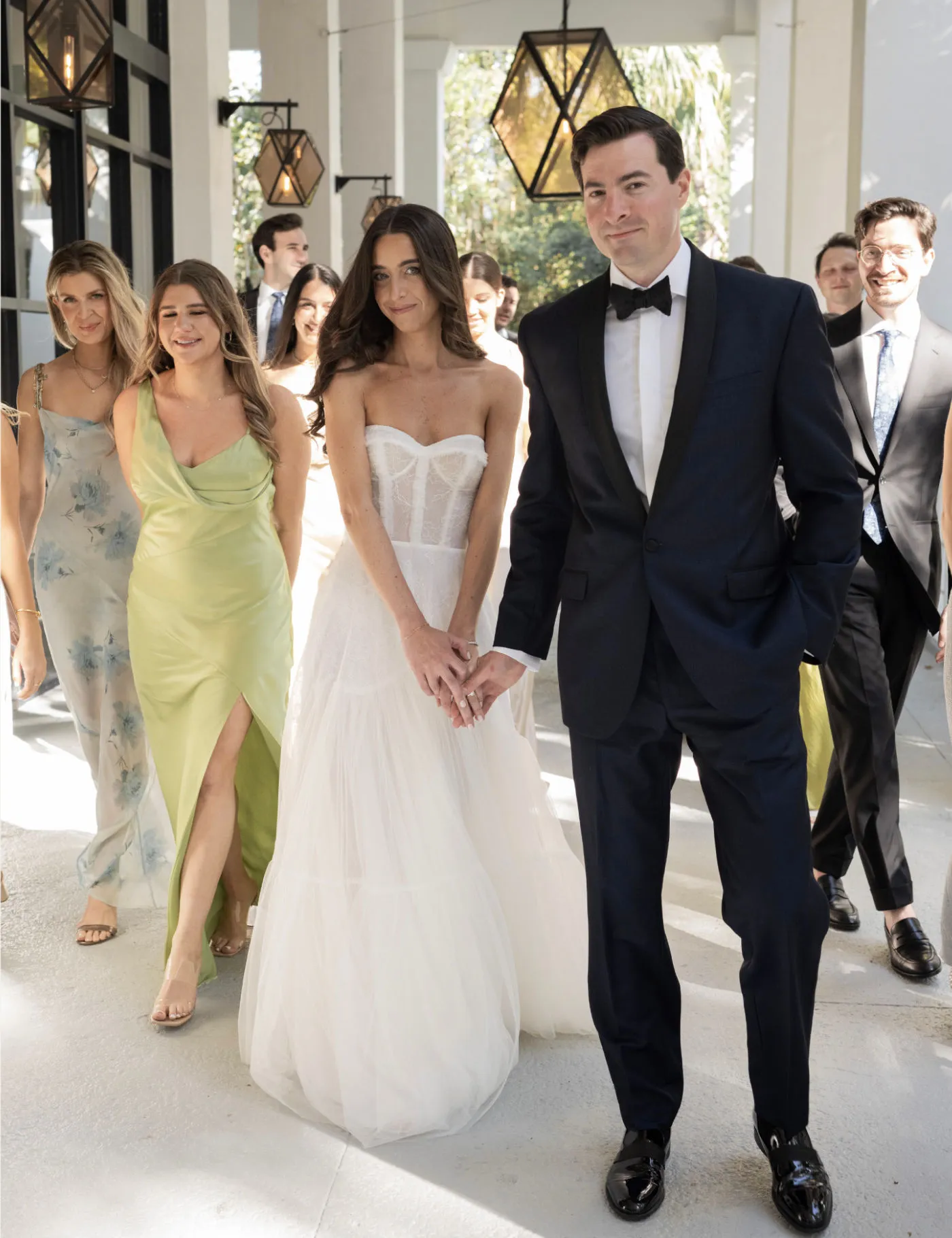 Bride and groom walking hand in hand with the wedding party behind them