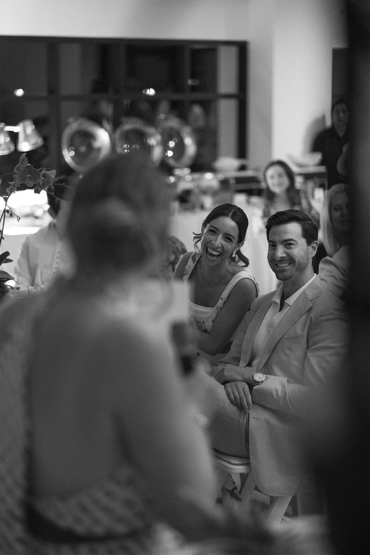 Two guests laughing together during speeches at a reception table