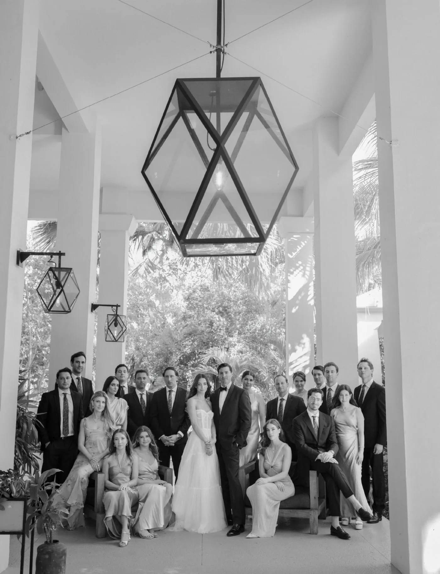 Wedding party portrait under a large geometric lantern on a covered terrace