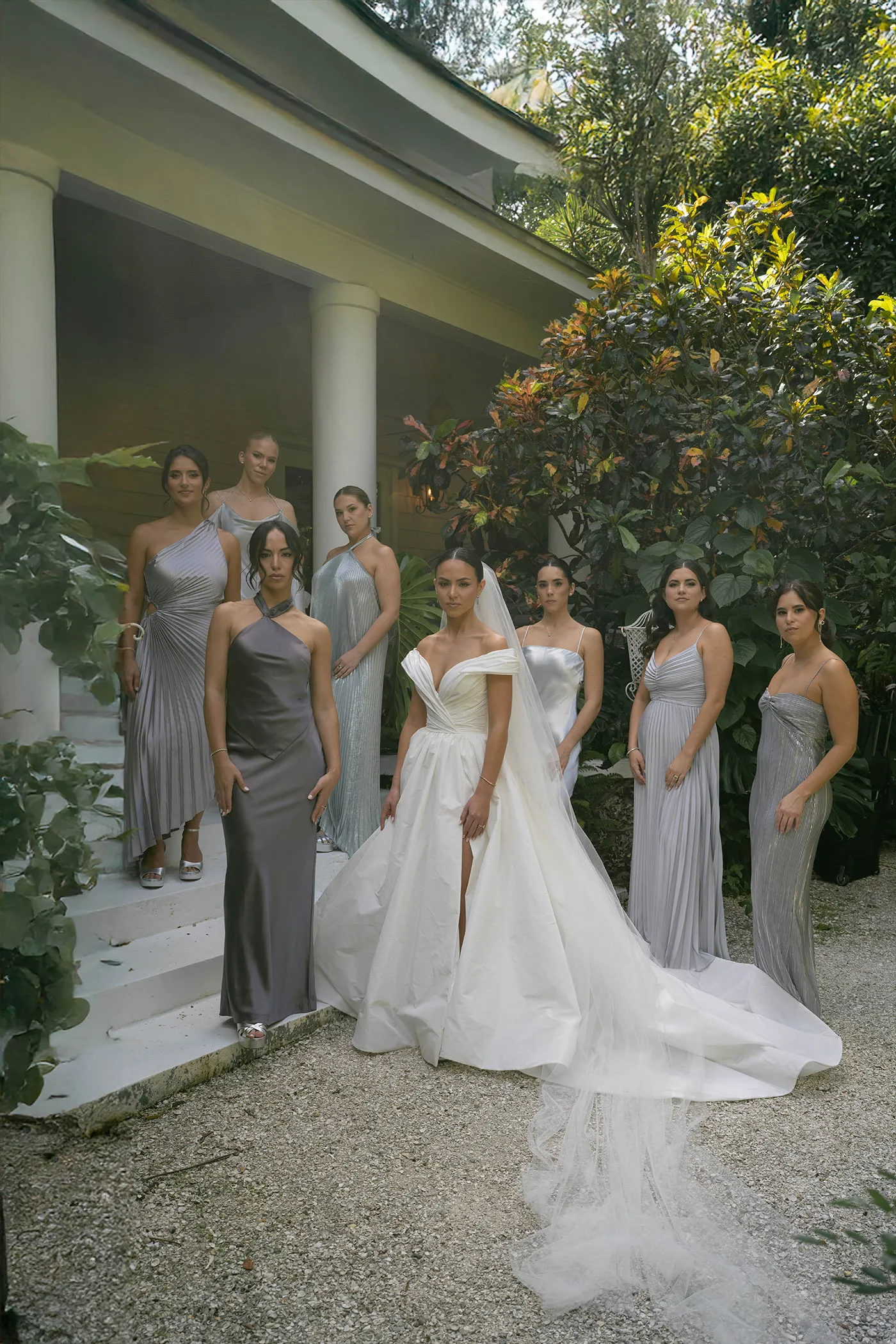 Bride and seven bridesmaids in silver gowns on garden steps