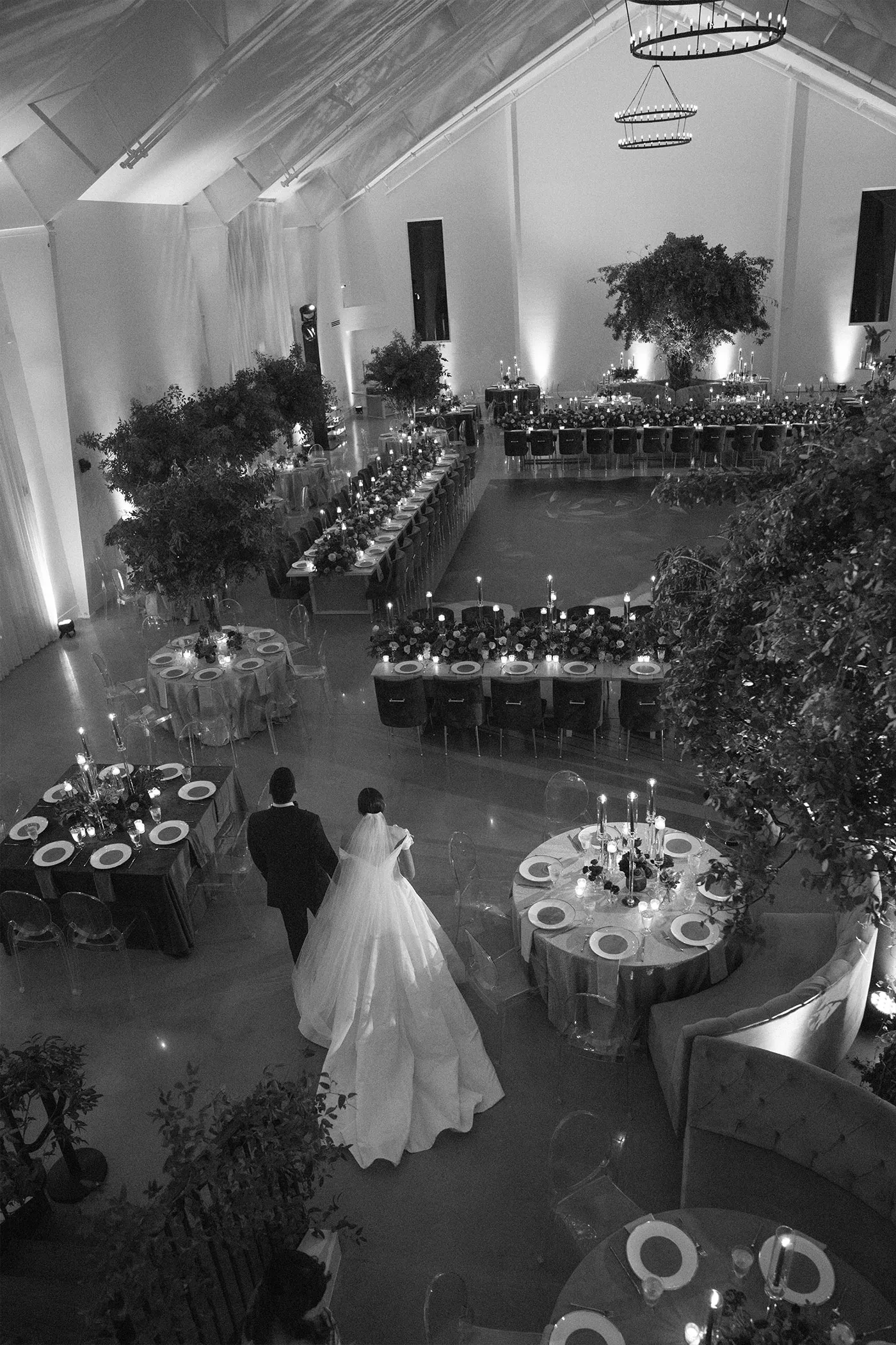Overhead view of a bride and groom walking into a set reception hall before guests arrive