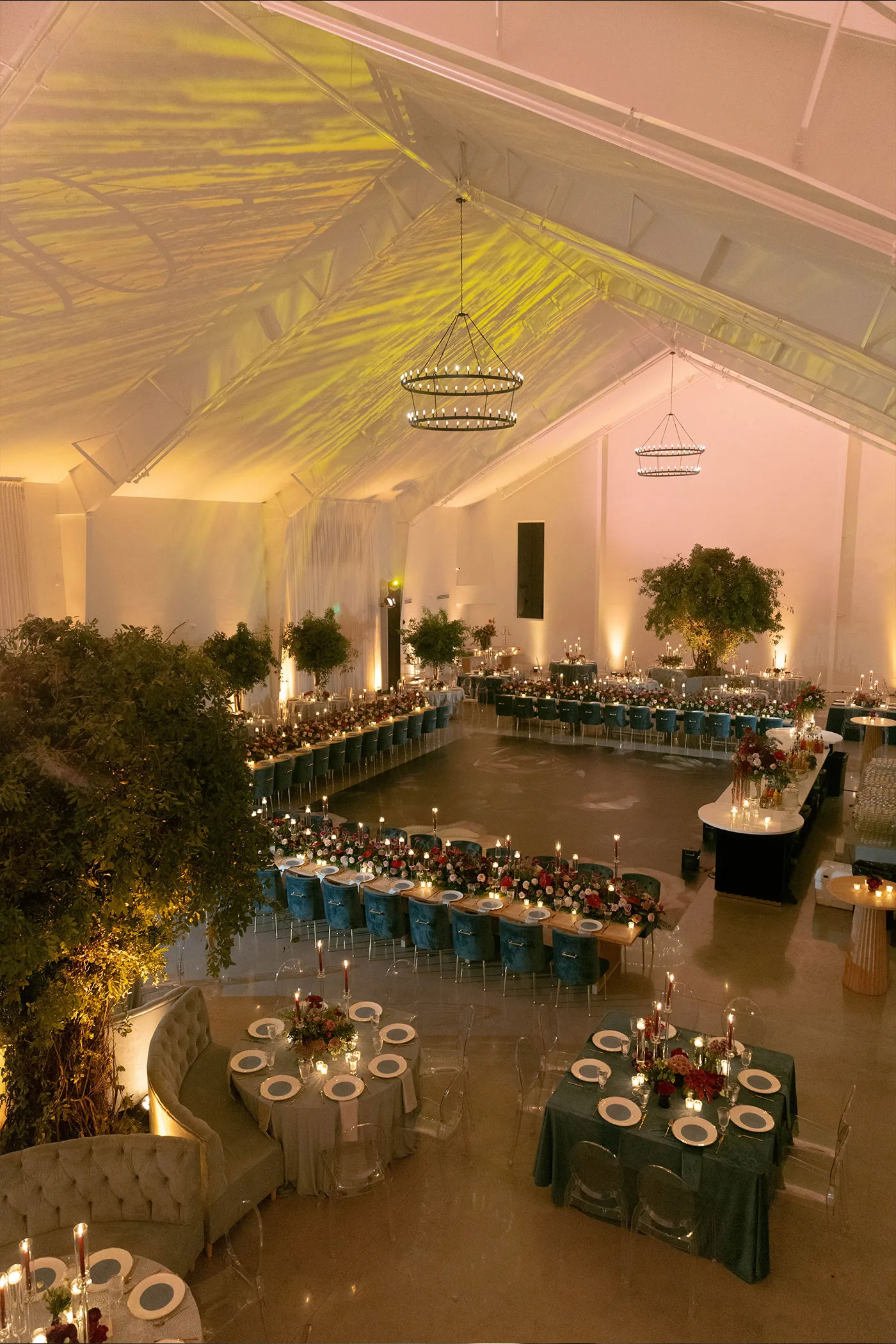 Tented reception hall from above with long banquet tables and chandeliers