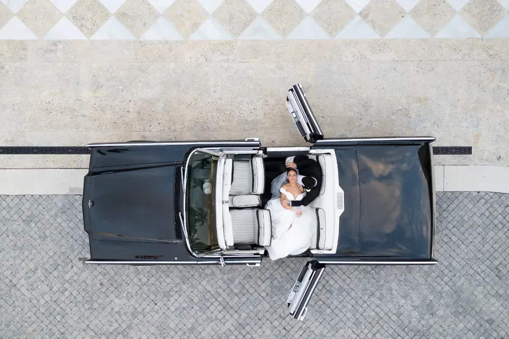 Overhead view of a bride and groom seated in an open vintage convertible