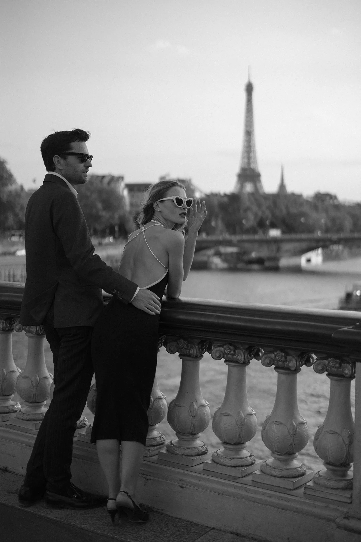 Couple at a bridge railing above the river, the Eiffel Tower behind them