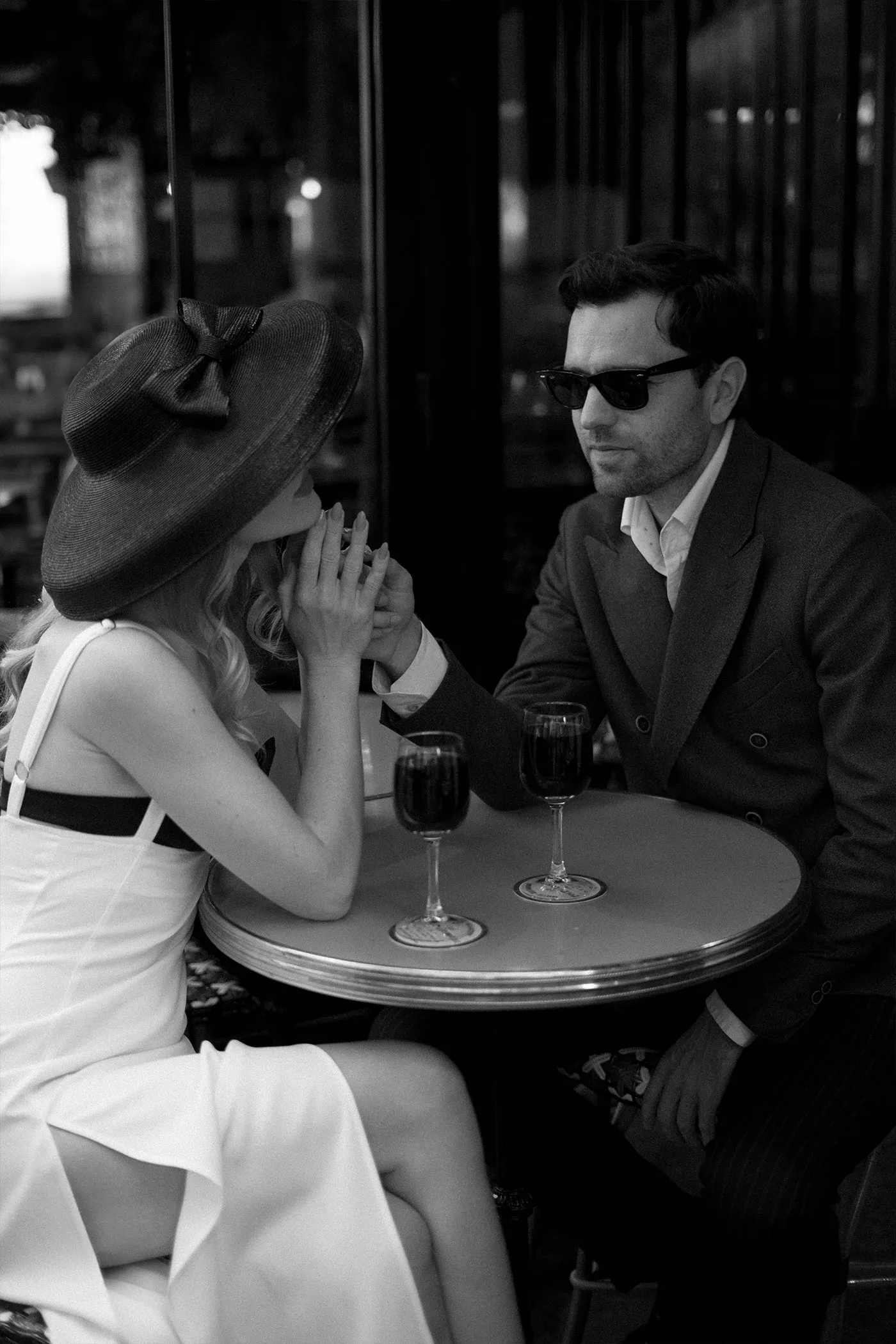 Couple holding hands across a small cafe table with two glasses of red wine