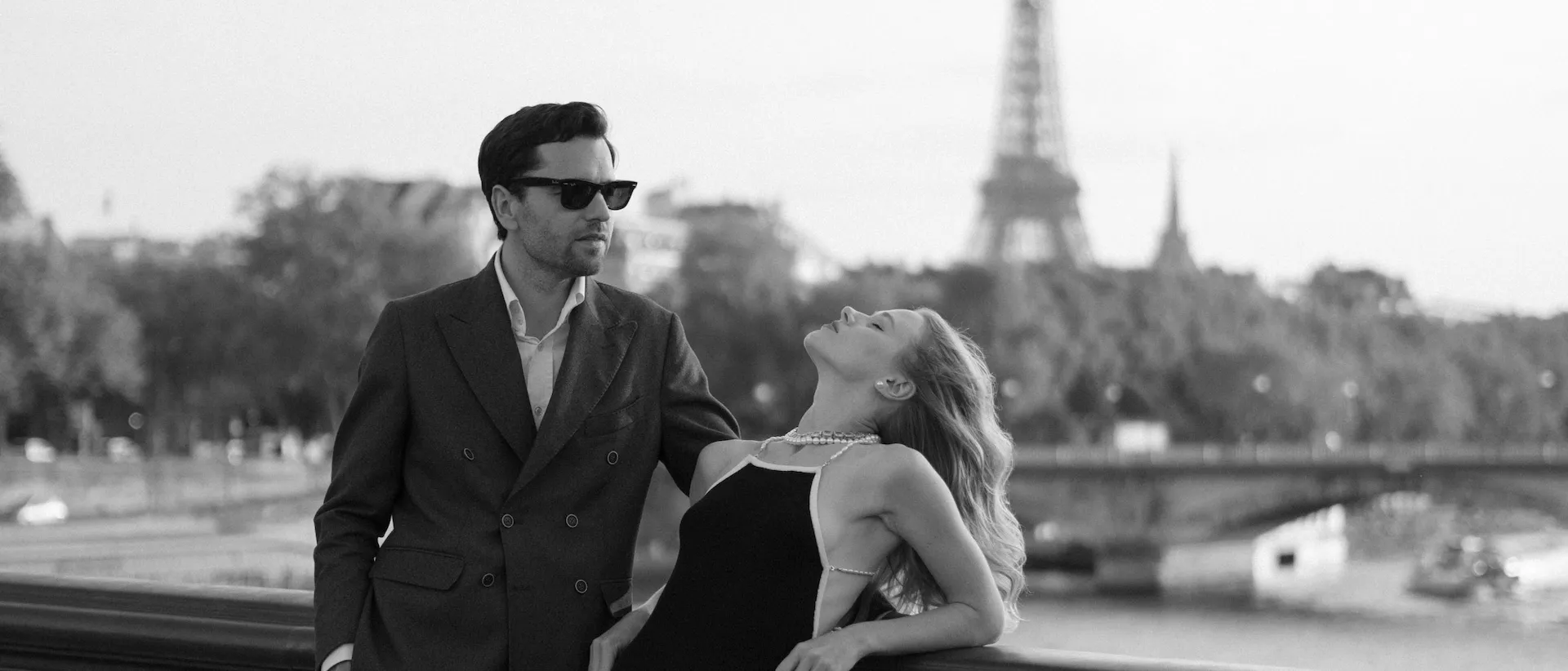 Couple leaning on a bridge railing, the Eiffel Tower behind them