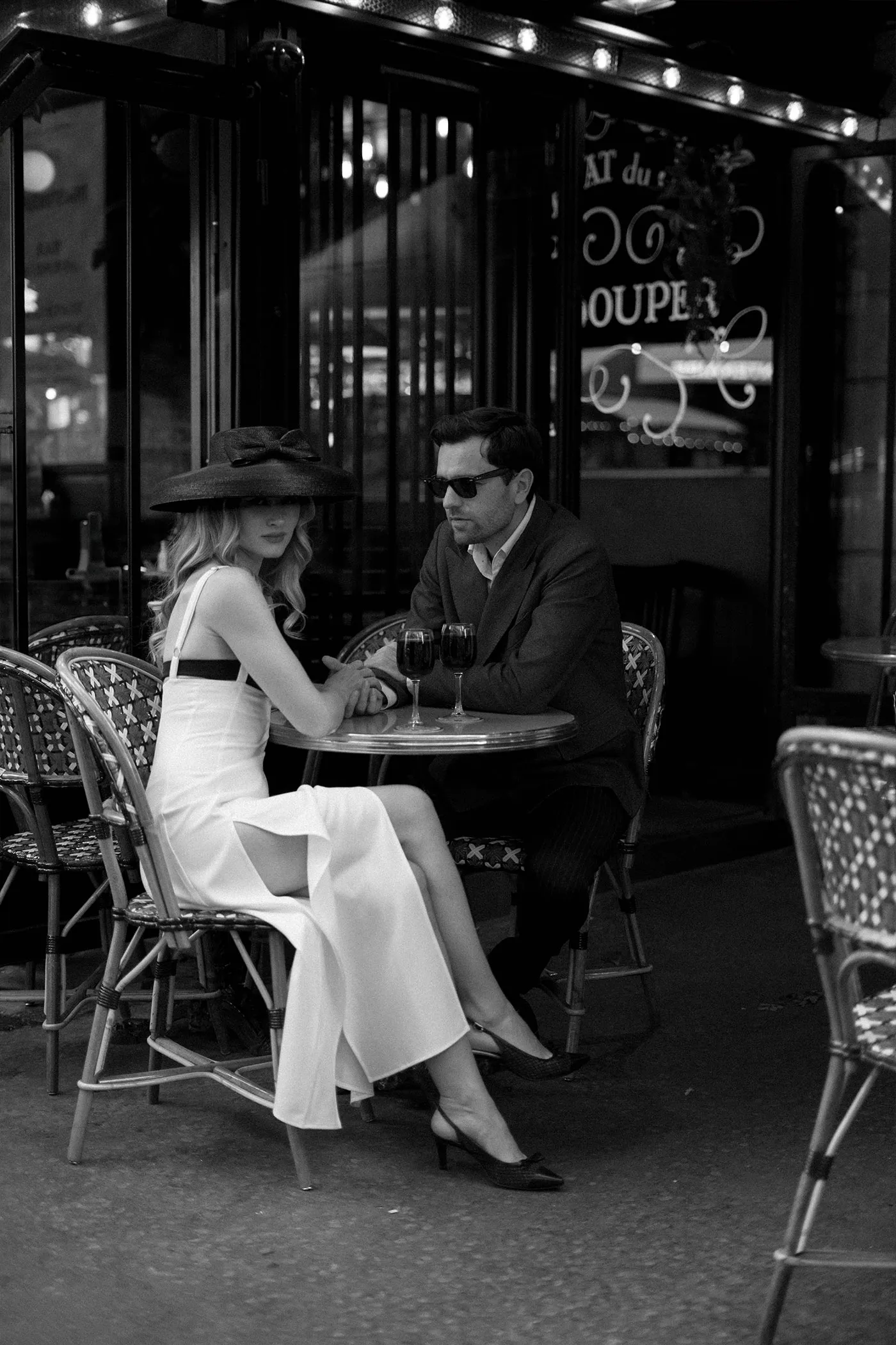 Couple holding hands at an outdoor cafe table with two glasses of red wine