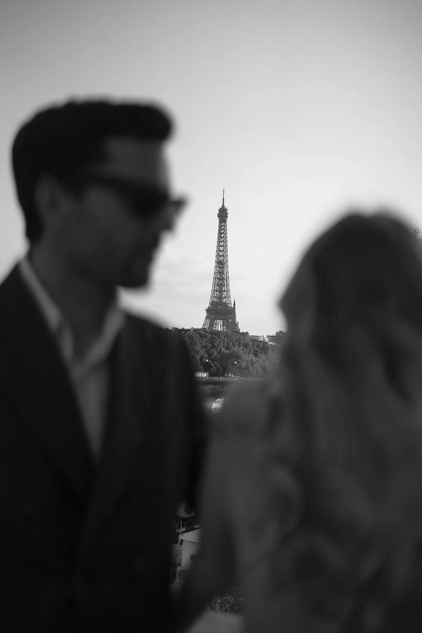Eiffel Tower framed between the out-of-focus heads of a couple, black and white