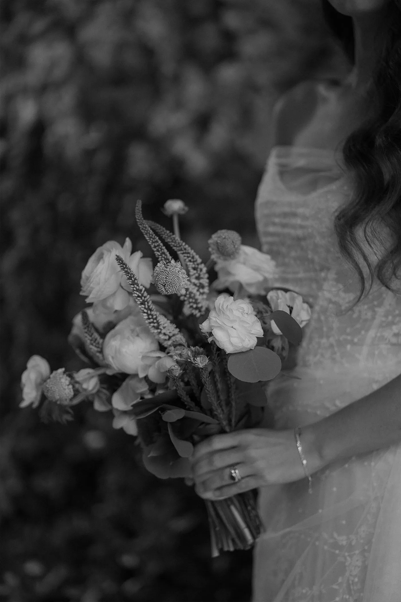 Bride's hands holding a loose garden bouquet against her beaded gown