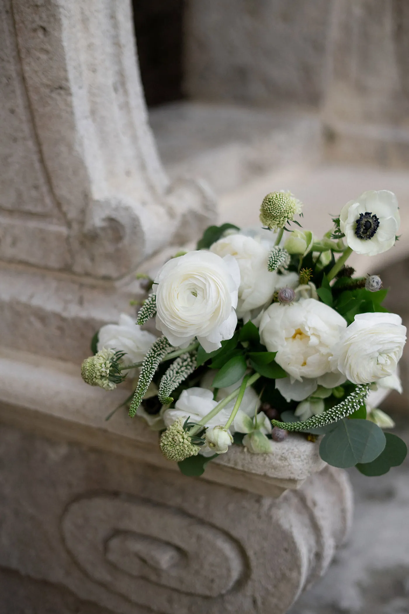 White ranunculus and anemone bouquet resting on carved stone steps