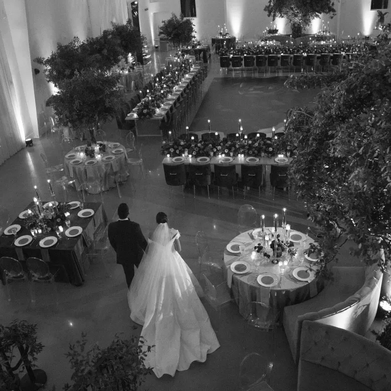 Bride and groom walking into a candlelit reception room seen from above