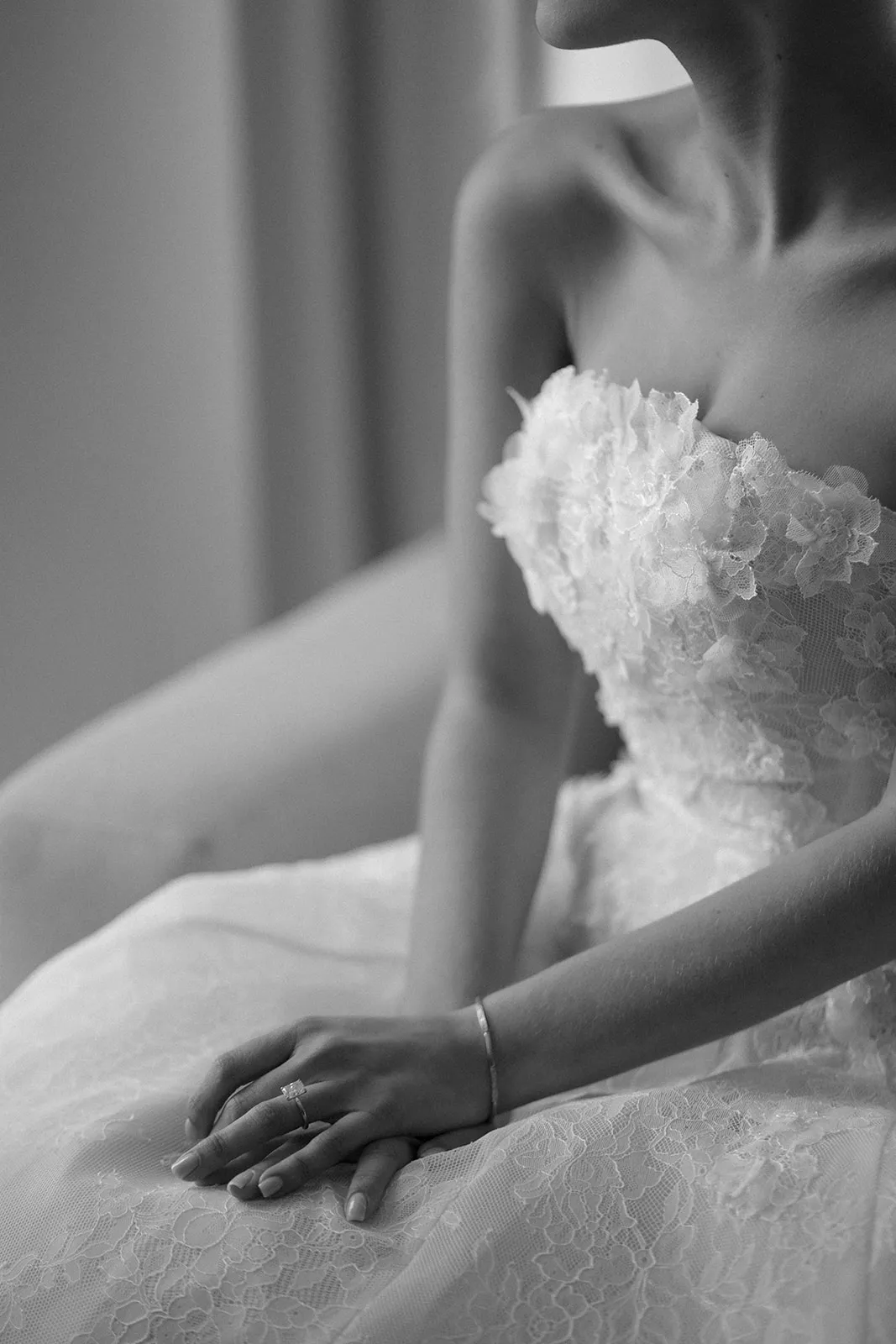 Bride's hand and lace corset bodice in soft window light, in black and white