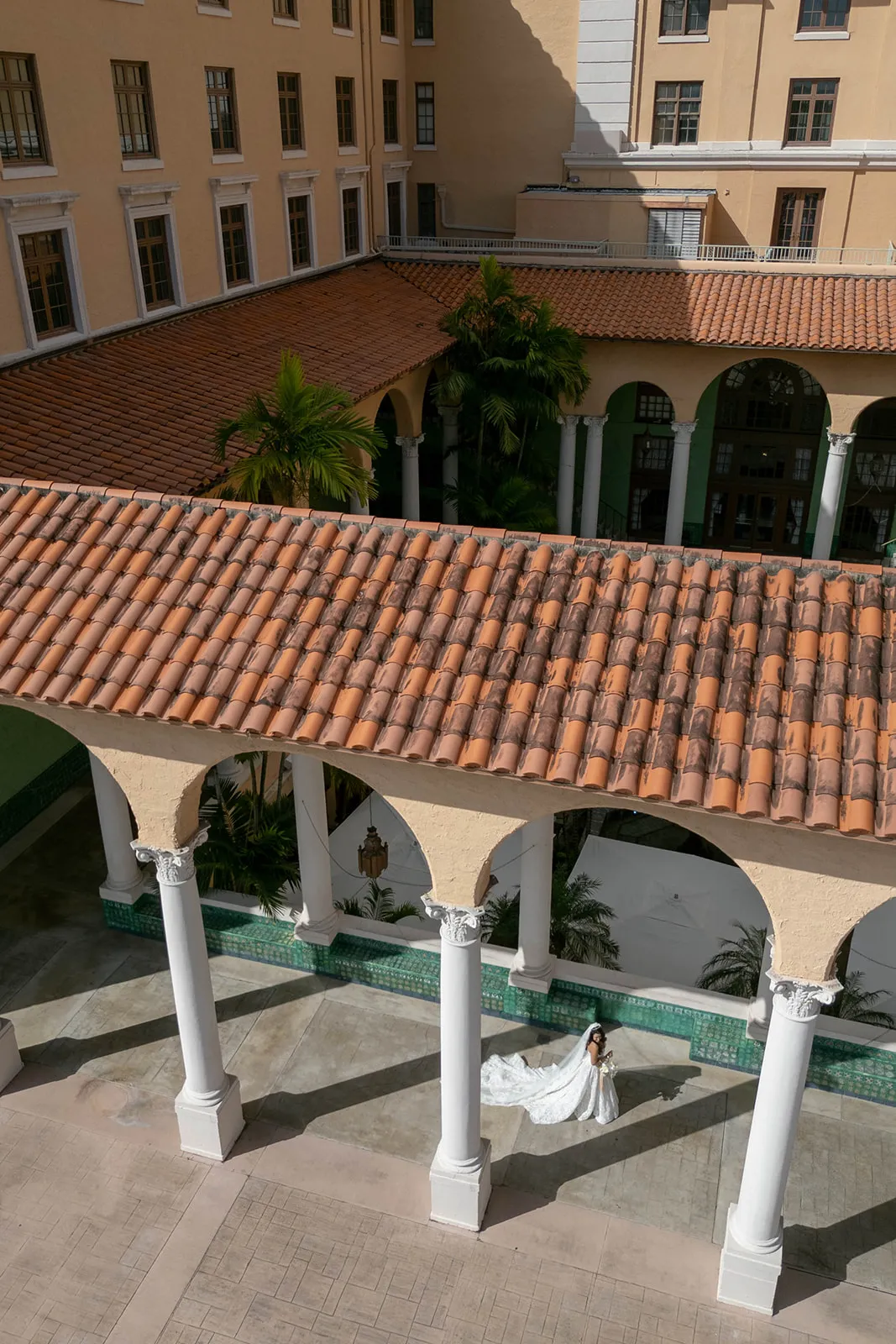 Bride with a long train alone in a tiled courtyard seen from above