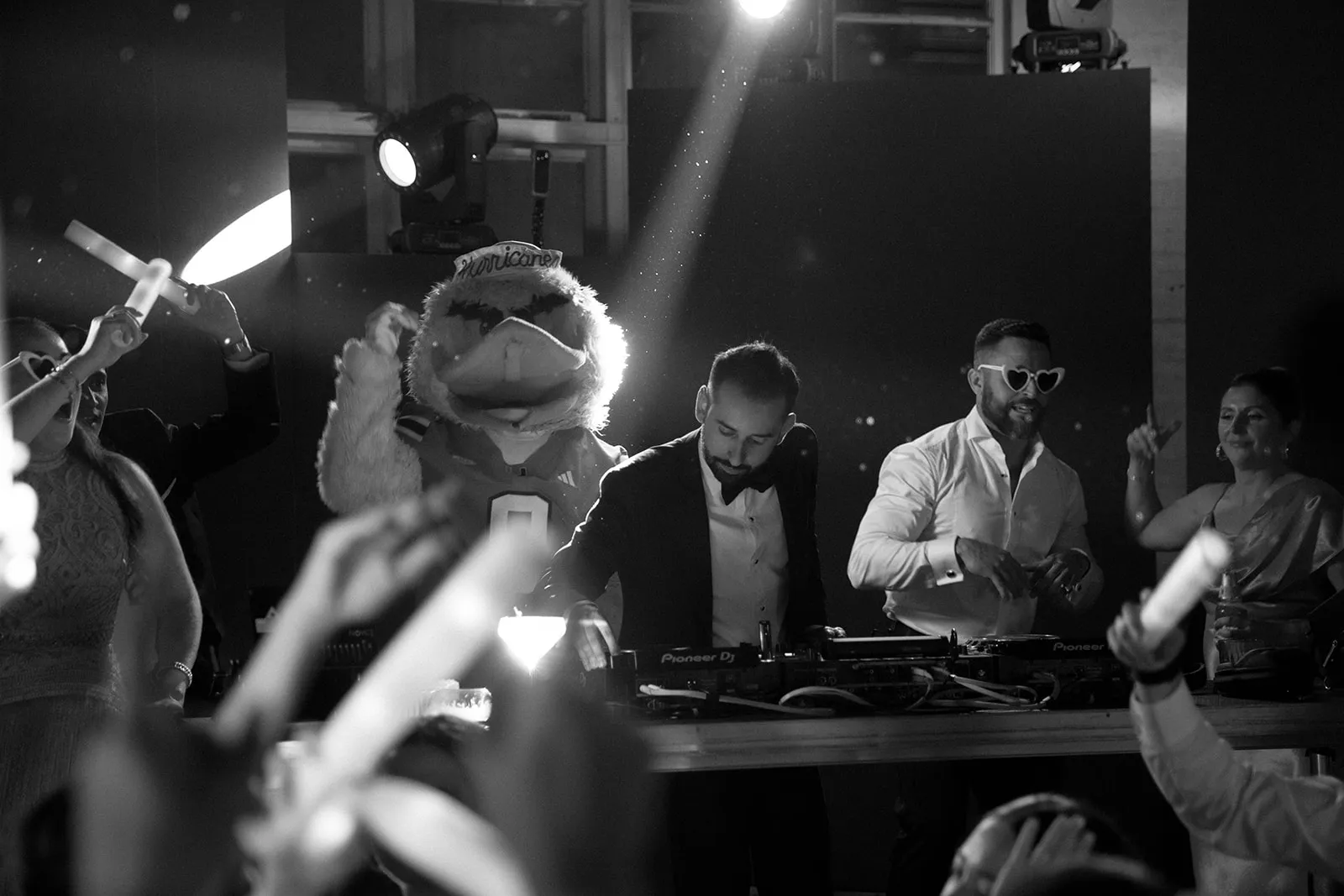 Costumed bird mascot dancing at the DJ booth as guests wave glow sticks