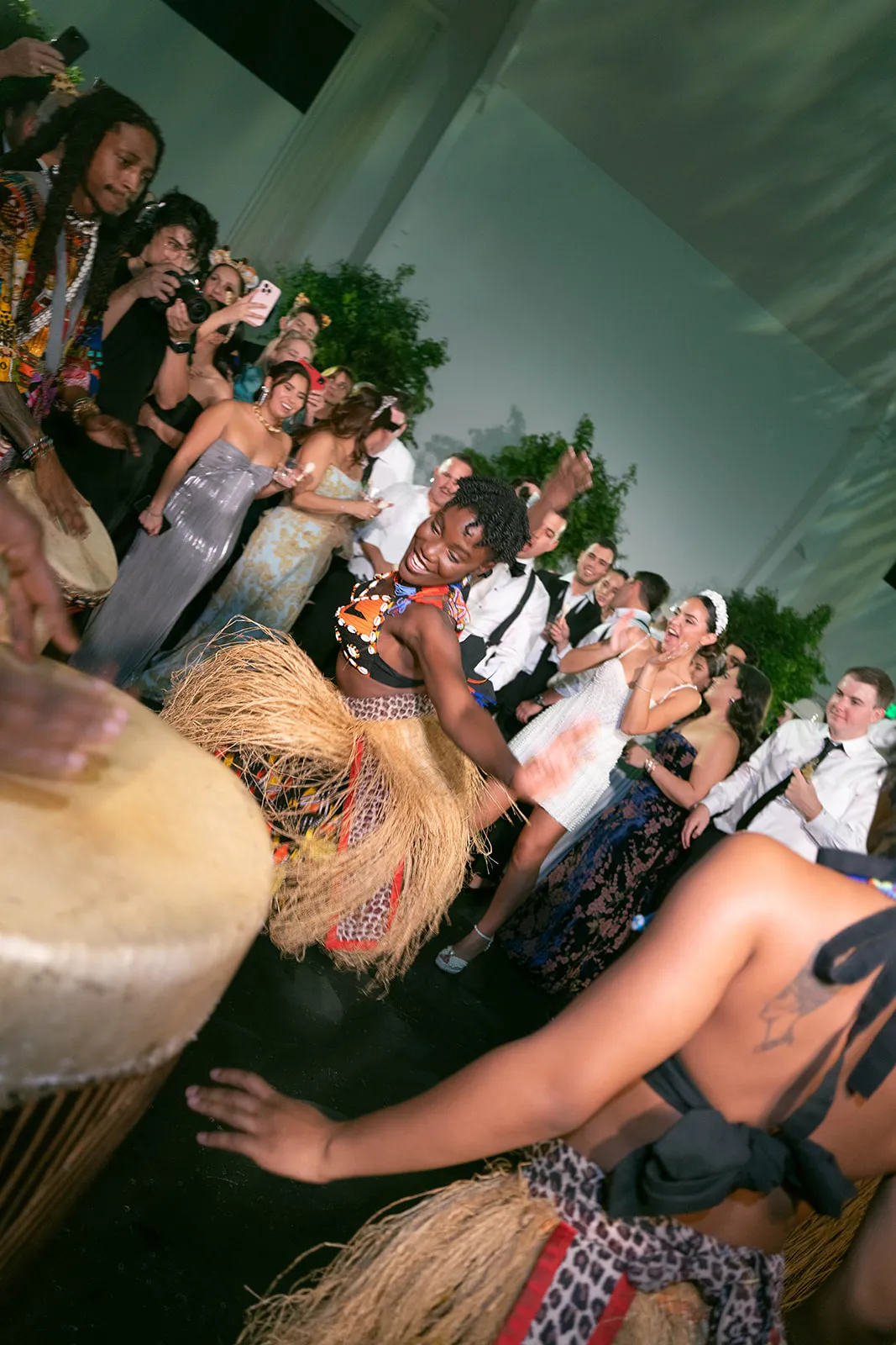 Costumed dancers and drummers performing as guests cheer at a reception