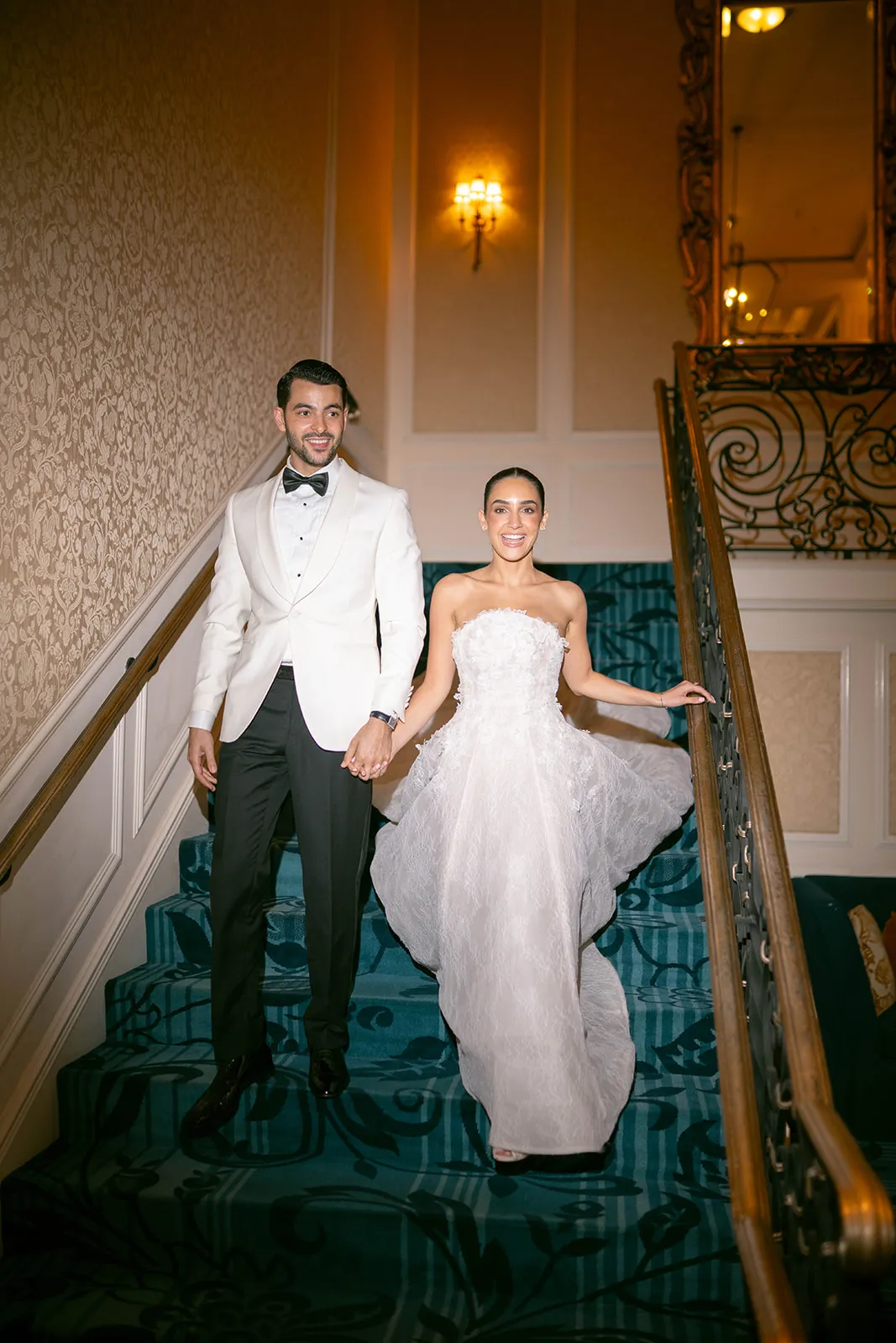 Couple holding hands as they walk down a carpeted staircase