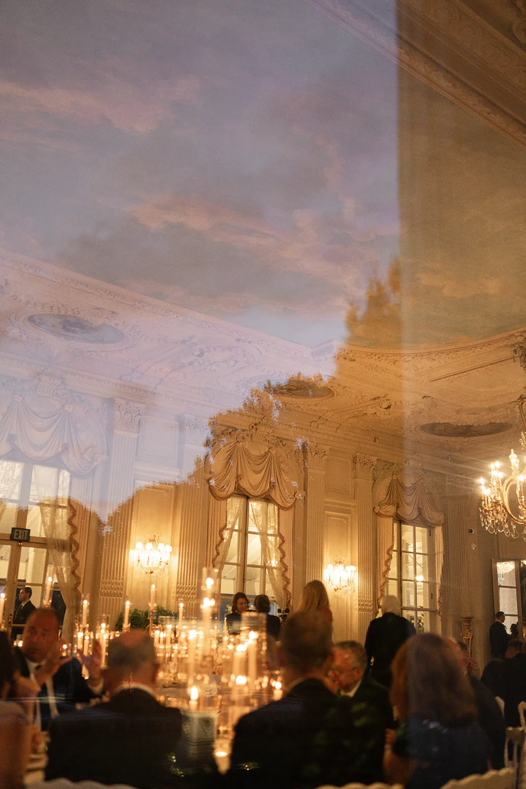 Double exposure of a candlelit ballroom dinner over a dusk sky