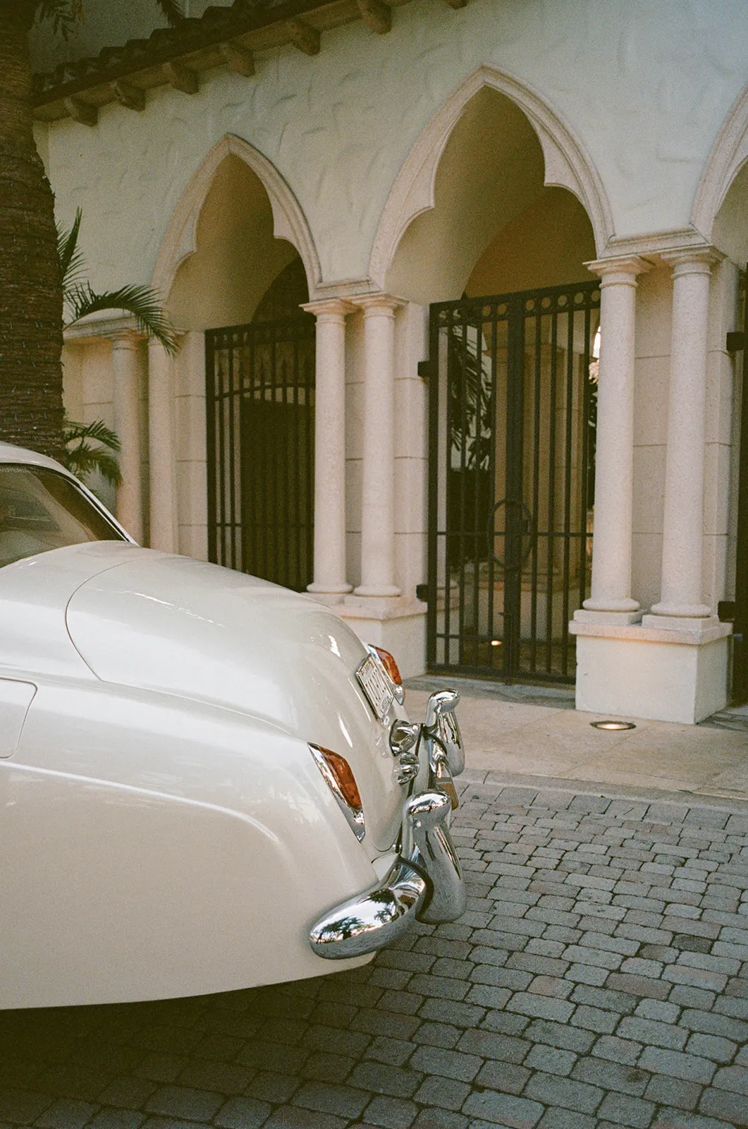 Vintage cream car parked outside an arched Mediterranean-style entrance